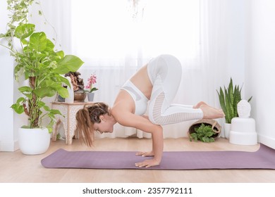 Woman practicing headstand pose while doing yoga at home. Bakasana or Crow Pose. Sports and healthy lifestyle concept. - Powered by Shutterstock