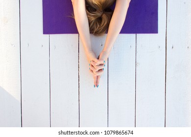 Woman Practicing Outdoors On Violet Yoga Mat. Overhead Close Up Of Female Hands In Mudra On White Wooden Background