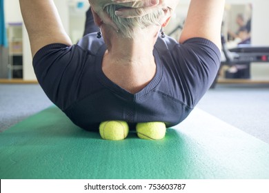 A woman practicing self-massage technique with tennis ball