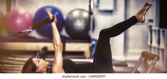Woman practicing stretching exercise on reformer in gym