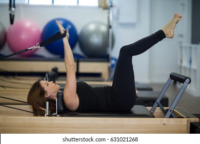 Woman practicing stretching exercise on reformer in gym