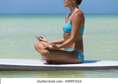 Woman practicing SUP yoga, on a paddleboard in the Caribbean