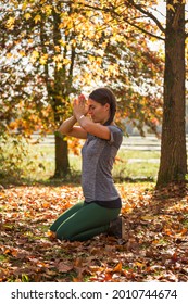 Woman Practicing Yoga In Autumn In Prayer Posture, Surrounded By Yellow And Golden Fall Leaves And Foliage