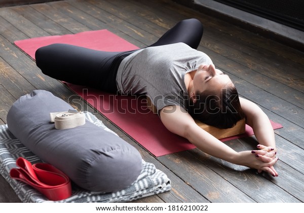 Woman practicing yoga, lying in Reclined\
Butterfly exercise, supta baddha konasana\
pose