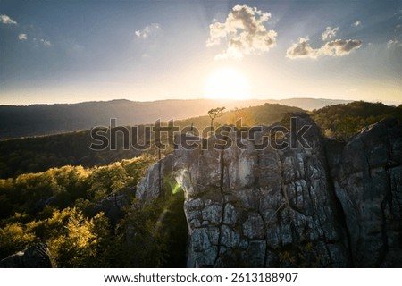 Woman practicing yoga and meditation on the top of huge boulder in the evening. Beautiful sunset, autumn forests, rocks and hills on background. Aerial drone view