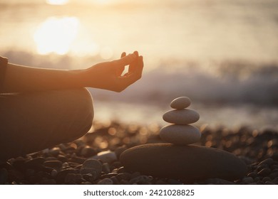 Woman practicing yoga and meditation and pyramid of pebbles on the beach, zen, harmony, spiritual concept, peace of mind - Powered by Shutterstock