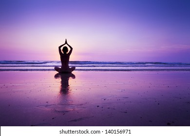 Woman practicing yoga on the beach at sunset in Koh Chang, Thailand