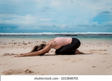 Woman Practicing Yoga On Ocean Beach - Child's Pose