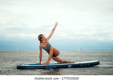 Woman practicing yoga on the paddle board in the morning. Photo without retouching