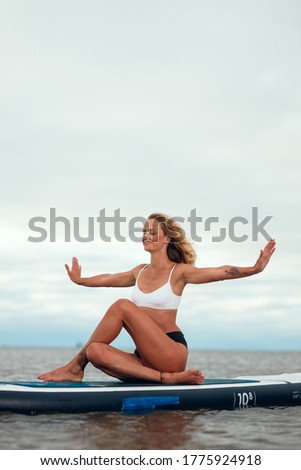 Woman practicing yoga on the paddle board in the morning. Photo without retouching