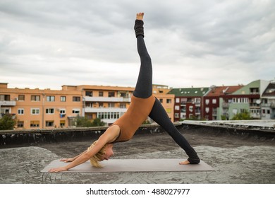 Woman Practicing Yoga On The Roof.Yoga-Adho Mukha Svanasana/Downward Facing Dog Pose, Left Leg Up