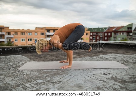 Woman practicing yoga on the roof.Yoga-Bakasana/Crane Pose