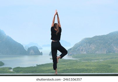 Woman practicing yoga on the sea view. Beautiful girl doing yoga on the steel  stand on the natural background of the ocean.
