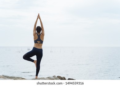 A woman practicing yoga postures on the beach