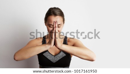 Woman practicing yoga, sitting in lotus position, hands together