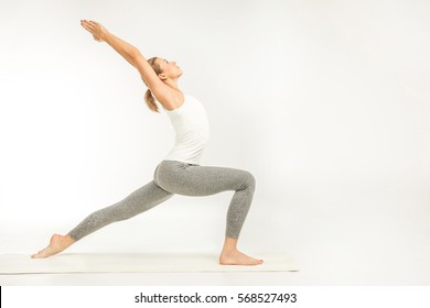 Woman practicing yoga standing in variation of Warrior I posture or Virabhadrasana One pose isolated on white