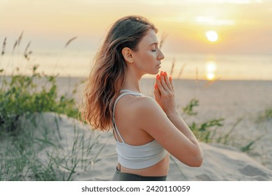 Woman practicing yoga at sunset on the beach, serene and peaceful.