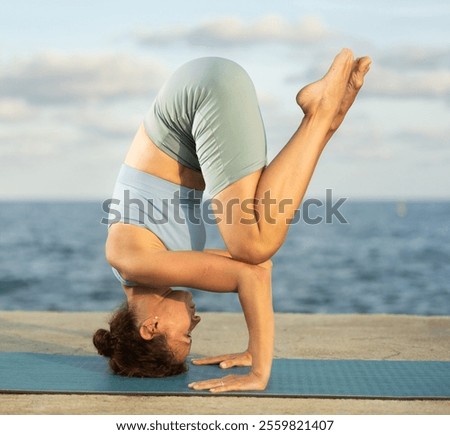 Similar – Image, Stock Photo Flexible woman performing headstand pose in yoga studio