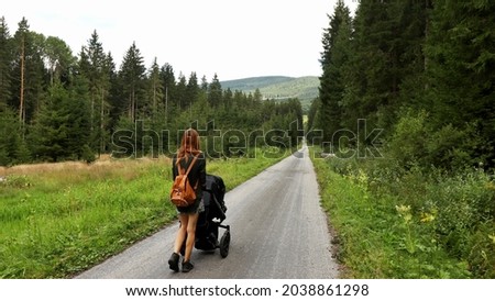 A woman with a pram on the road. Location: Europe, Czechia, near Horni plana