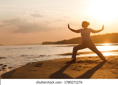 Woman praticing tai chi chuan at sunset on the beach. Chinese management skill Qi's energy. solo outdoor activities. Social Distancing 
