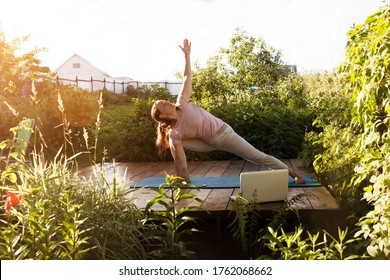 Woman praticing yoga outdoor, online laptop lesson. Healthy lifestyle concept. solo outdoor activities.  - Powered by Shutterstock