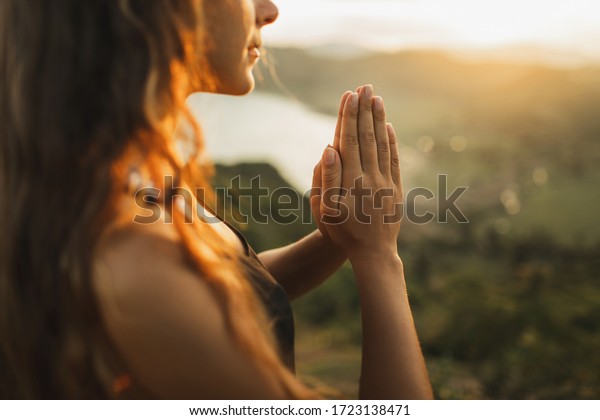 Woman praying\
alone at sunrise. Nature background. Spiritual and emotional\
concept. Sensitivity to\
nature