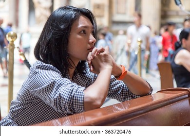 Woman praying in church. Young woman meditating on a bench in church. Woman has clasped hands in prayer in the Christian church. Religious woman praying in church. Supplication wish to God.