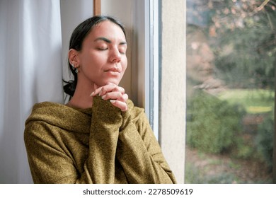 Woman praying as an expression of trust, optimism, and perseverance, as she seeks to find meaning - Shutterstock ID 2278509619