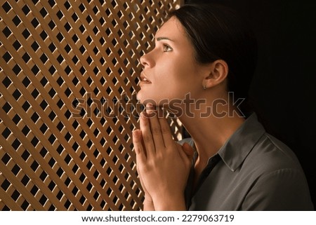 Woman praying to God during confession in booth