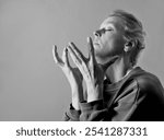 woman praying to god with hands together on grey black background with people stock photo stock image	