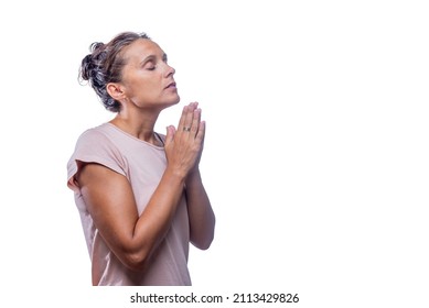 A woman praying with hands clasped and eyes closed