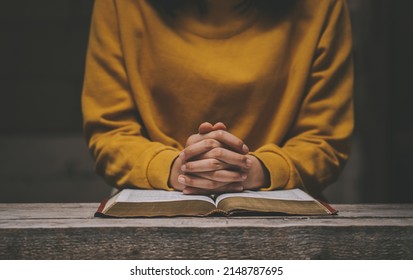 Woman praying on holy bible in the morning. Holding hands in prayer on a wooden table. Christian life crisis prayer to god. Hands folded in prayer on a Holy Bible in church concept for faith.