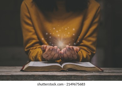 Woman praying on holy bible in the morning have a Yellow lights and sparkles coming. Woman hand with Bible praying. Christian life crisis prayer to god. - Shutterstock ID 2149675683