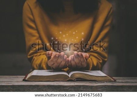 Woman praying on holy bible in the morning have a Yellow lights and sparkles coming. Woman hand with Bible praying. Christian life crisis prayer to god.