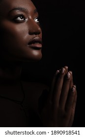 Die Frau betet. Porträt einer schönen Afrikanerin, die betet. Eine junge Christin taucht während des Gebets in Meditation ein. Das Gesicht und die Hände sind aufgeklärt.