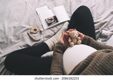Woman pregnant belly with little teddy toy bear. Concept image with symbol of many meanings for expectant mother during pregnancy and her unborn baby.