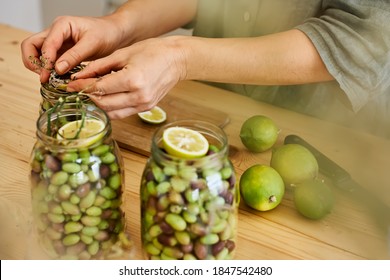 Woman prepares fermented olives in glass jars in the kitchen. Autumn vegetables canning. Healthy homemade food. Conservation of harvest. Defocused foreground. - Powered by Shutterstock