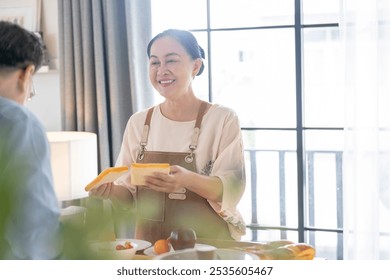 A woman prepares fresh vegetables in a cozy kitchen, while a man assists in the background. The scene emphasizes a warm and healthy lifestyle with a focus on fresh produce and home cooking. - Powered by Shutterstock