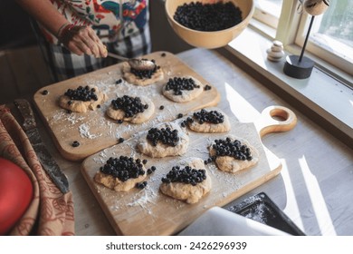 Woman preparing blueberry buns at home 
(Jagodzianka - traditional Polish sweet bun filled with blueberries) - Powered by Shutterstock