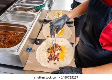 Woman preparing burrito in a food truck putting the ingredients in Tortilla bread - Powered by Shutterstock