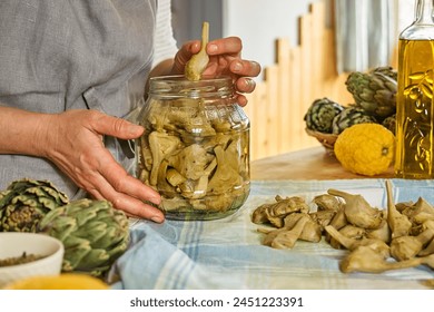 Woman preparing canned italian artichokes in olive oil. Artichoke hearts pickled with olive oil and herbs. Homemade healthy eating. - Powered by Shutterstock