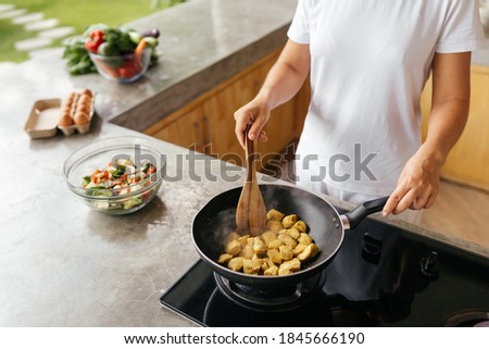woman preparing chiken breasts , healthy meal in her rustic eco open kitchen