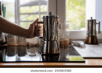 Woman preparing coffee at home kitchen setting near window, girl holding a modern stainless geyser coffee pot on induction stove panel indoor, geyser coffee maker - Powered by Shutterstock