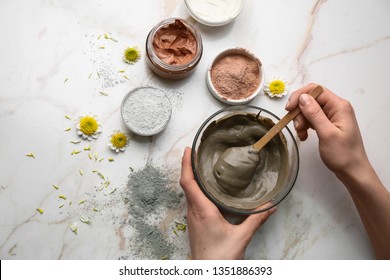 Woman preparing cosmetic clay on light background
