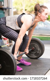 Woman Preparing To Do A Weight Lifting Deadlift Movement In A Home Gym (garage).