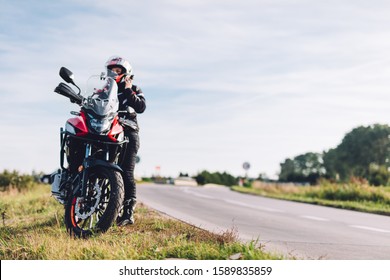 Woman preparing to drive a motorbike. Wearing helmet on a roadside - Powered by Shutterstock