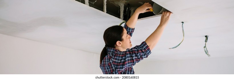 Woman Preparing Extractor Hood Installation On Kitchen Ceiling