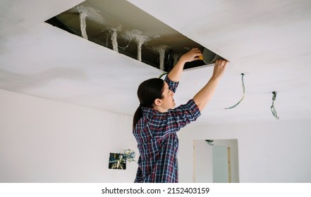 Woman Preparing Extractor Hood Installation On Kitchen Ceiling