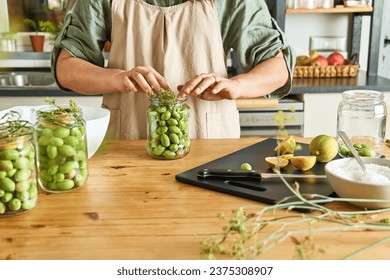 Woman preparing fermented olives in glass jar with slices of lemon, wild fennel and canning brine. Autumn vegetables canning. Healthy homemade food. Conservation of harvest. - Powered by Shutterstock