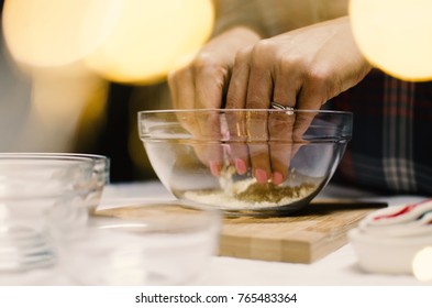 Woman Preparing Food In The Kitchen, Using Hands To Mix Flour In Glass Bowls.  Holiday Preparation For Dessert And Meal.